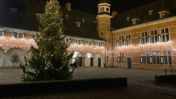 A courtyard with a Christmas tree and a building with a tower.