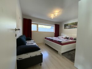 Una camera da letto con un letto, un divano, una finestra e un quadro appeso al muro.