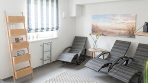 A room with a window, a painting, a chair, a small table, and a wooden ladder. - Modern comfort in Föhr's prime location (Nieblum)