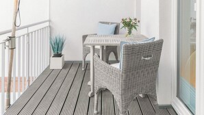 A balcony with a table and chairs, a potted plant, and a ceiling fan. - Modern comfort in Föhr's prime location (Nieblum)