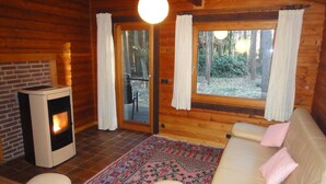 Un accogliente interno di una baita con camino, un divano e un tappeto decorato.