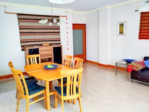 Un comedor con una mesa y sillas de madera, un tazón azul sobre la mesa, y una pared con diseño al fondo.