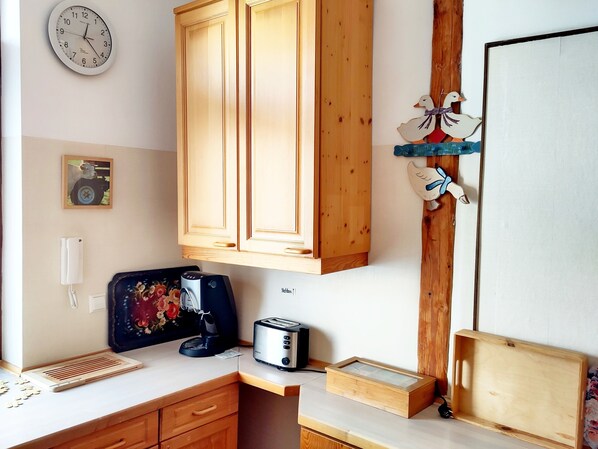 A kitchen with wooden cabinets, a clock, a toaster, and a decorative wall piece.