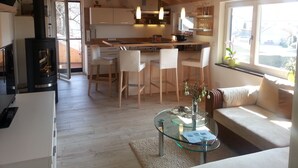 A modern kitchen with a central island, wooden chairs, and a glass coffee table.