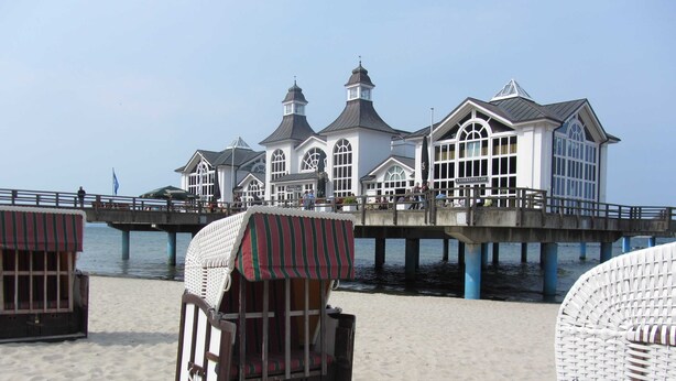 A beachside pier with beach chairs and a building with a sign reading 'RAISERPAVILLON'. - Wittow - Pension Waldrose (Sellin)