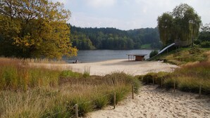 Ranta, jossa on puinen rakennelma, köysisilta ja taustalla metsäinen kukkula.