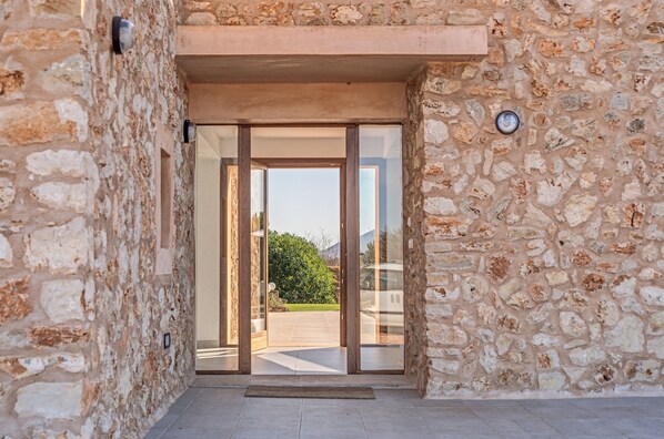 Une entrée en pierre, avec une porte en verre donnant sur un patio.