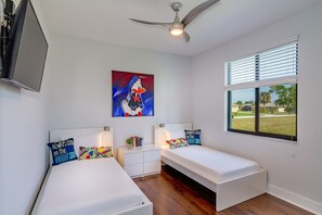 A bedroom with two beds, a ceiling fan, a window with blinds, and a painting on the wall. - VILLA AVIVA - modern, boat-lift, large south-facing terrace with spa/pool (Cape Coral)