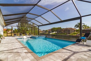 A swimming pool with a covered area, lounge chairs, and a view of a residential neighborhood. - VILLA AVIVA - modern, boat-lift, large south-facing terrace with spa/pool (Cape Coral)
