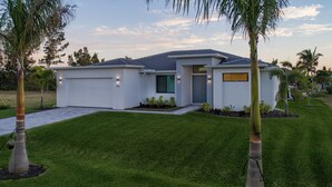 Une maison moderne de plain-pied, dotée d’une pelouse bien entretenue, d’un garage et d’un petit jardin.