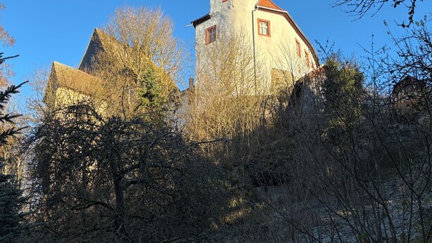 Un bâtiment historique doté d’une tour imposante et d’une grande structure en pierre en premier plan.