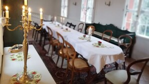 Une salle à manger avec une longue table dressée pour un repas, des chandeliers et un lustre.
