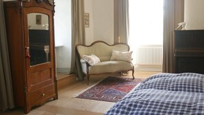 Une chambre avec une armoire en bois, un canapé, un tapis à motifs et un lit avec une literie à carreaux.