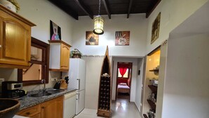 Una cucina compatta con mobili in legno, un frigorifero, una macchina da caffè e una dispensa per il vino.