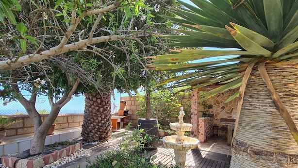 Un patio con una fontana in pietra, un'area barbecue e vista sul mare.