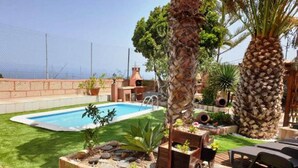 Un cortile con piscina, palme e area barbecue.