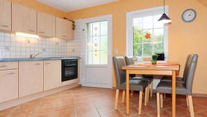A kitchen with wooden cabinets, a built-in oven, and a dining area with a table and chairs. - Non smoking apartment, ideal for 2 to 4 persons, quiet place suitable for allergy sufferers, (Stedesdorf)