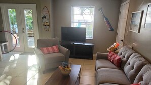 Ein Wohnzimmer mit Sofa, Sessel, Couchtisch und Fernseher.