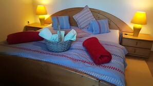 A neatly made bed with patterned bedding, a basket of toiletries, and two bedside lamps. - Best starting point for bikers, hikers, mushroom and nature lovers in the national park  (Bohinj -Koprivnik)