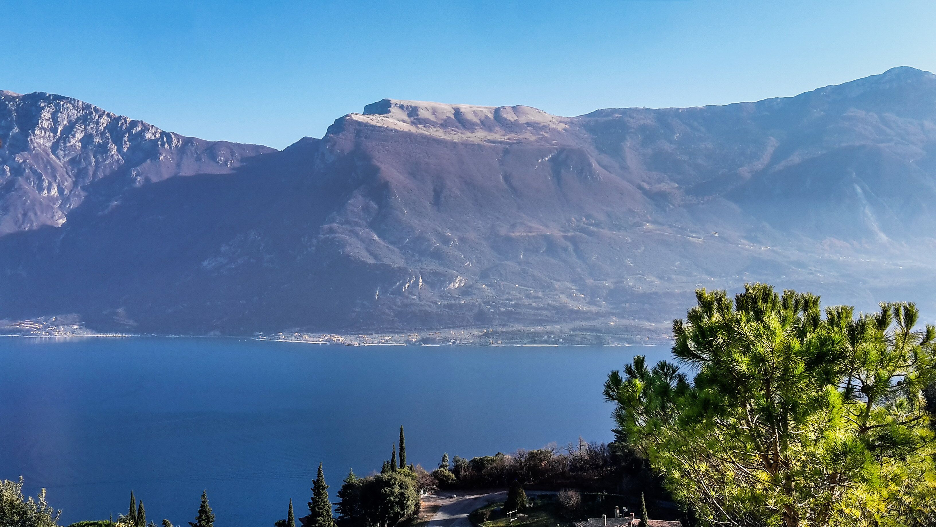 A mountainous landscape with a clear view of a lake and a small settlement in the distance.