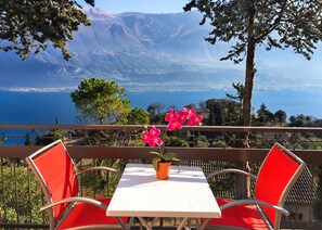 Una terraza con mesa y sillas, con vistas a un paisaje pintoresco de un lago y montañas.