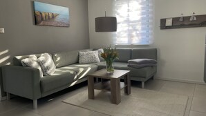 Una sala de estar moderna con un sofá gris, una mesita de madera con un florero y un cuadro en la pared.
