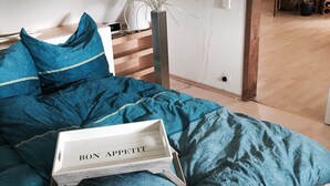 Un lit avec une couette à motifs bleus, une table de chevet avec une lampe et une tête de lit en bois.