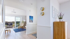 Un salon moderne avec une grande fenêtre, un meuble en bois et un tapis à motifs bleus.
