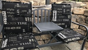A metal outdoor chair with a black cushion featuring white text. - Beautiful barrier-free 3 1/2 room apartment near the beach!  (Allensbach)