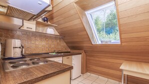 A kitchen with a wooden ceiling, a window, a stove, and a dishwasher. - 3-Bedroom Apartment  (Grömitz)