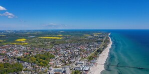 An aerial view of a coastal town with a beach, buildings, and a bridge.