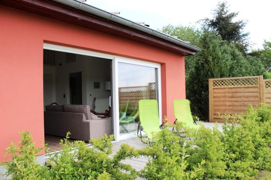 Wohnbereich mit großem Schiebefenster und angrenzender Holzterrasse