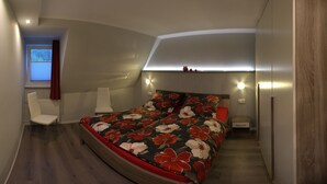 A modern bedroom with a curved ceiling, a bed with a floral bedspread, a chair, and a nightstand.