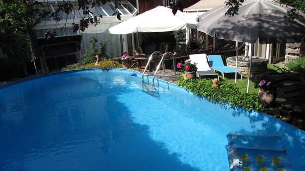 Une piscine avec un plongeoir, des chaises longues et des parasols.
