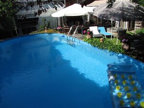 Ein Schwimmbecken mit Sprungbrett, Liegestühlen und Sonnenschirmen.