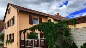 Un bâtiment à deux étages, doté d’une façade marron, d’un toit en tuiles et d’une entrée fermée par un portail.