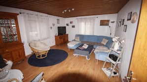 Un salon chaleureux avec un canapé bleu, un fauteuil en osier et un meuble en bois.