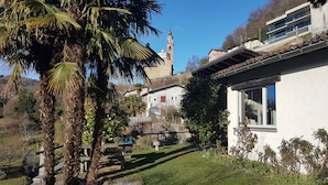 A white building with a stone wall, a palm tree, and a church tower in the background. - Nice Mediterranean holiday home. Ideal for families, athletes etc. Nature lovers (Carona)