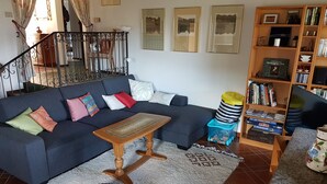 A living room with a dark blue sofa, a wooden coffee table, and a bookshelf filled with books and decorative items. - Nice Mediterranean holiday home. Ideal for families, athletes etc. Nature lovers (Carona)