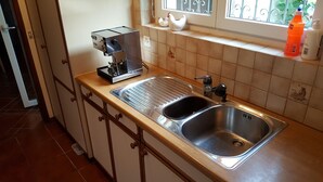 A kitchen with a stainless steel sink, a coffee maker, and a window with decorative items. - Nice Mediterranean holiday home. Ideal for families, athletes etc. Nature lovers (Carona)
