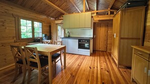 L’intérieur d’un chalet en bois comprend un coin repas, une petite cuisine et une grande fenêtre.