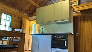 Une cuisine compacte dotée de meubles en bois, d’un four encastré et d’une fenêtre laissant entrer la lumière naturelle.
