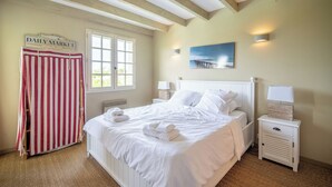 A bedroom with a bed, bedside tables, a nightstand, a radiator, a window, and a door.