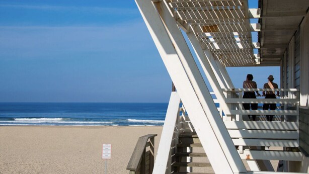 A beach with a lifeguard tower and a sign.