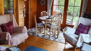 A cozy cabin interior with wooden walls, a dining area with a table and chairs, and a seating area with sofas.