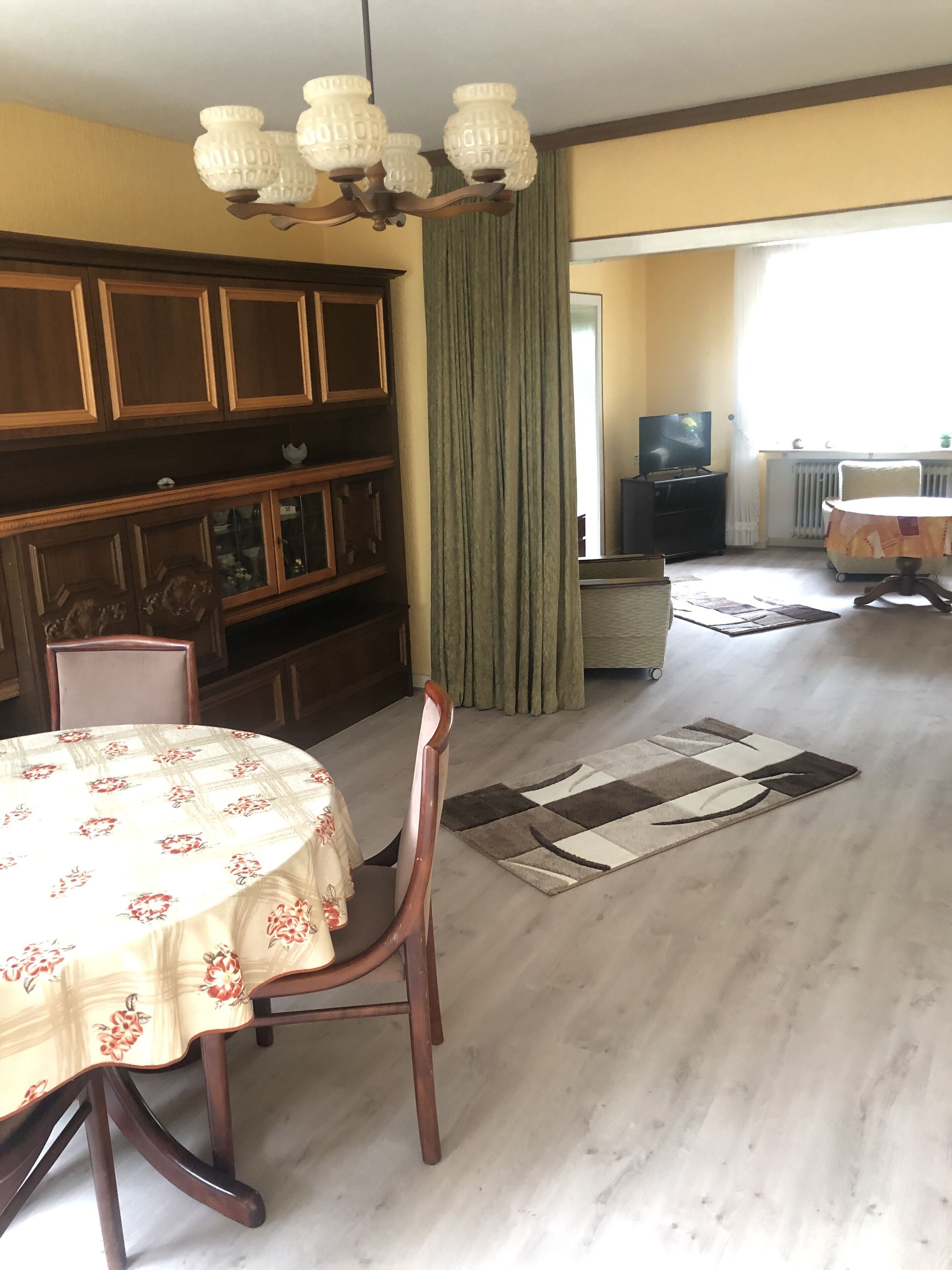 Un comedor con una mesa dispuesta para dos, un aparador de madera y un televisor al fondo.