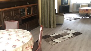 Un coin repas avec une table dressée pour quatre personnes, un buffet en bois et un téléviseur en arrière-plan.