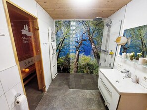 Une salle de bain équipée d’une douche, de toilettes, d’un lavabo et d’un miroir.