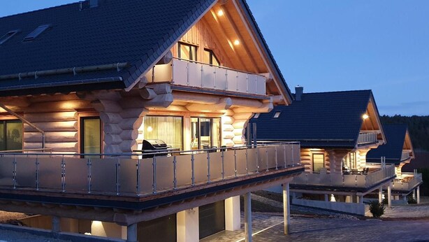 A log cabin with a balcony and a grill area. - Canadian log cabins in the Hunsrück with lake and national park views (Langweiler)