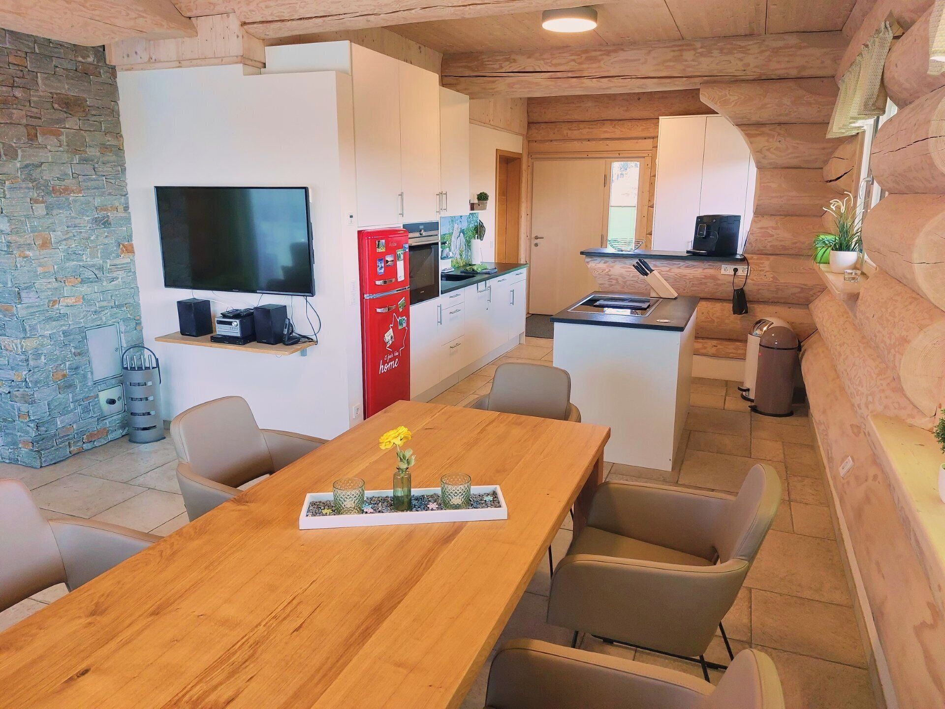 Un espacio habitable compacto con cocina, comedor y televisor montado en la pared.